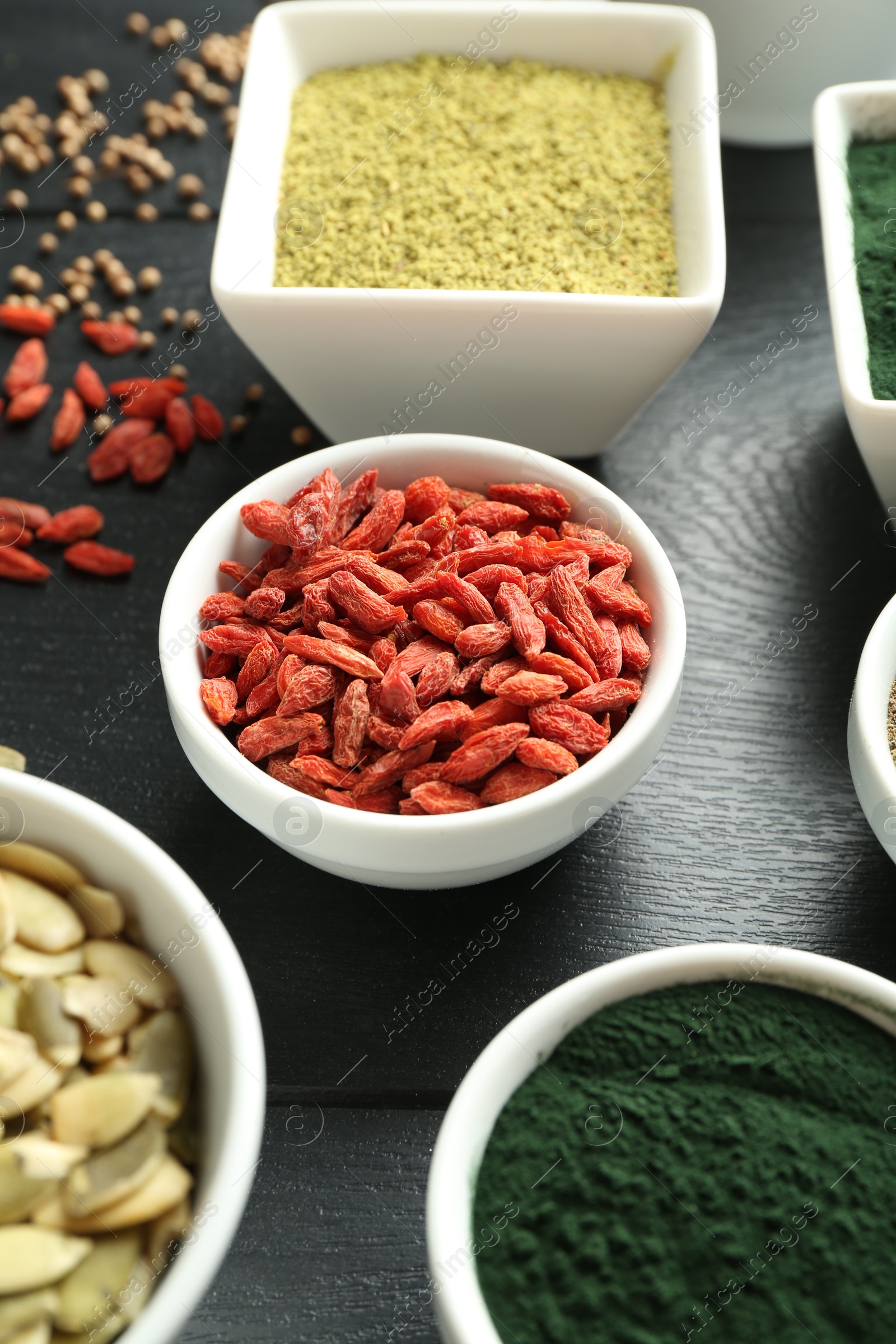 Photo of Different healthy superfoods in bowls on black wooden table