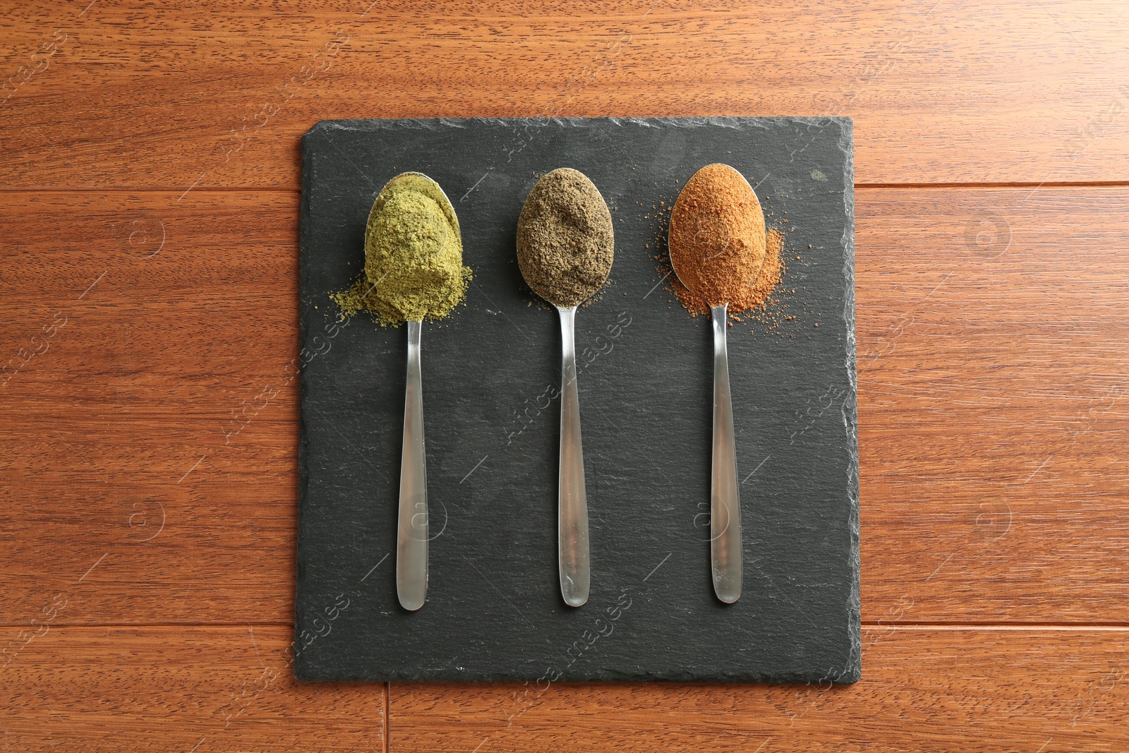 Photo of Different superfood powders in spoons on wooden table, top view