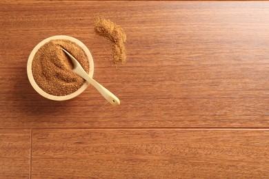 Superfood powder in bowl and spoon on wooden table, top view. Space for text