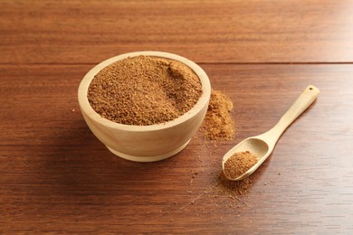 Photo of Superfood powder in bowl and spoon on wooden table