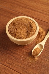 Photo of Superfood powder in bowl and spoon on wooden table