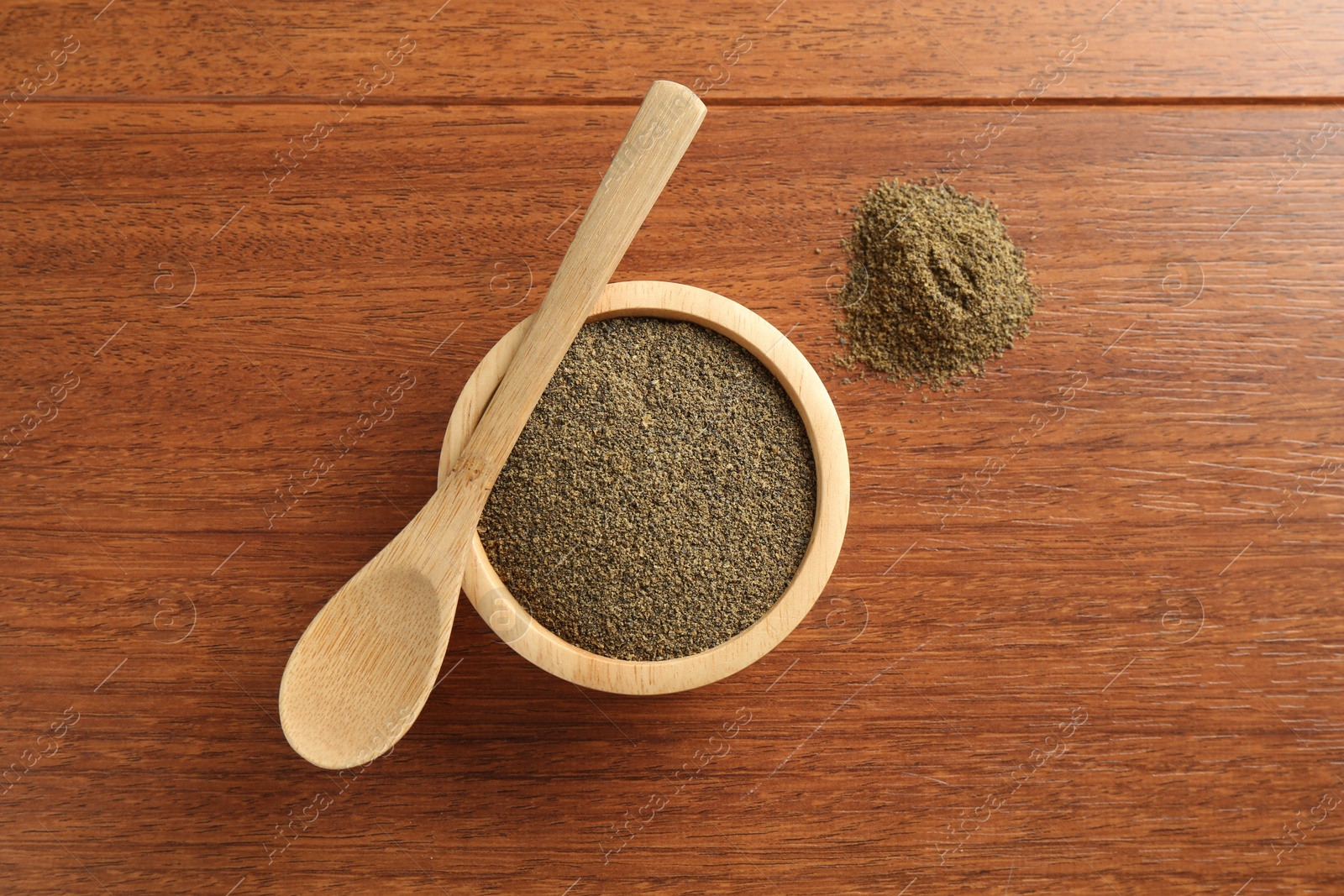 Photo of Superfood powder in bowl and spoon on wooden table, top view