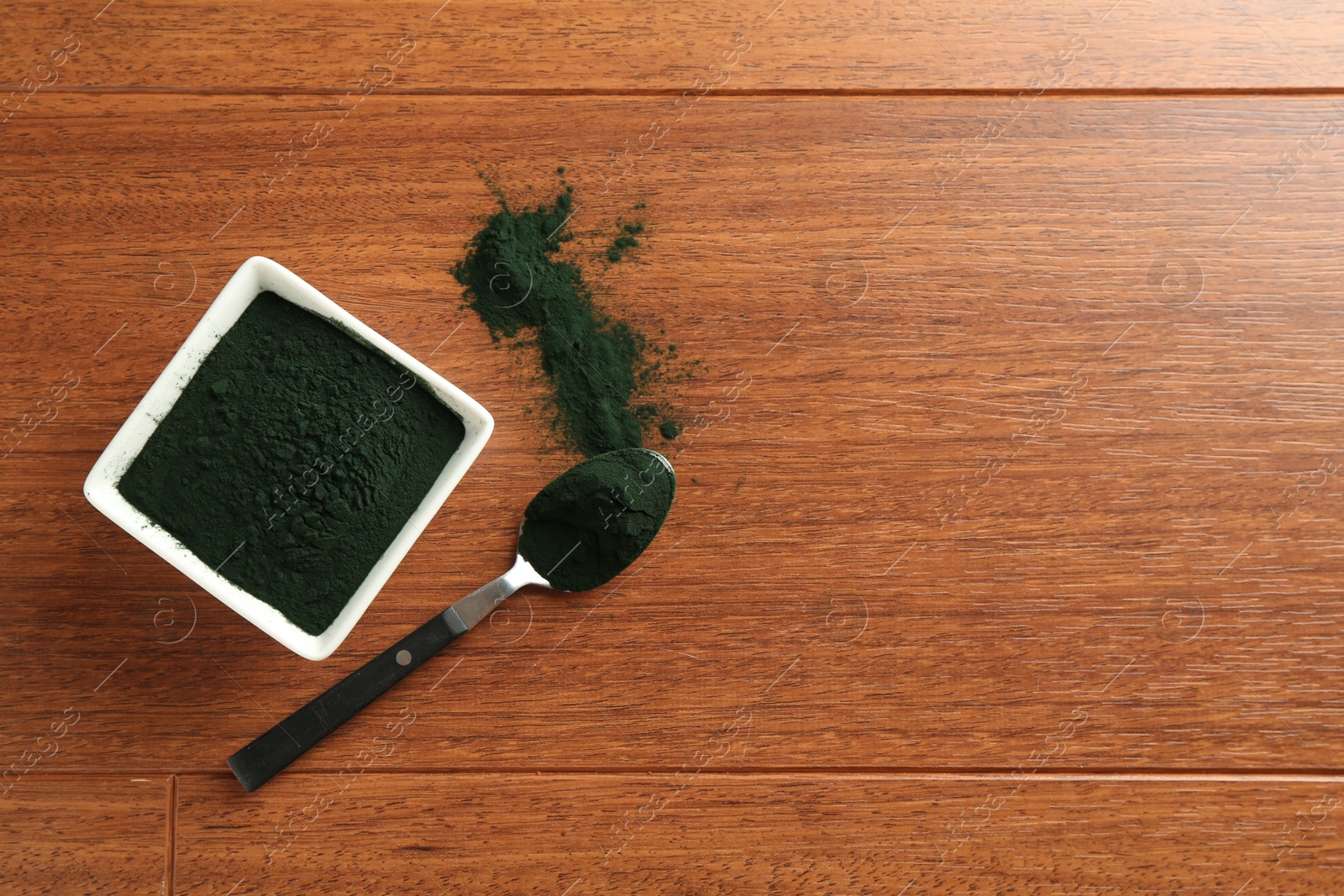 Photo of Superfood powder in bowl and spoon on wooden table, top view. Space for text