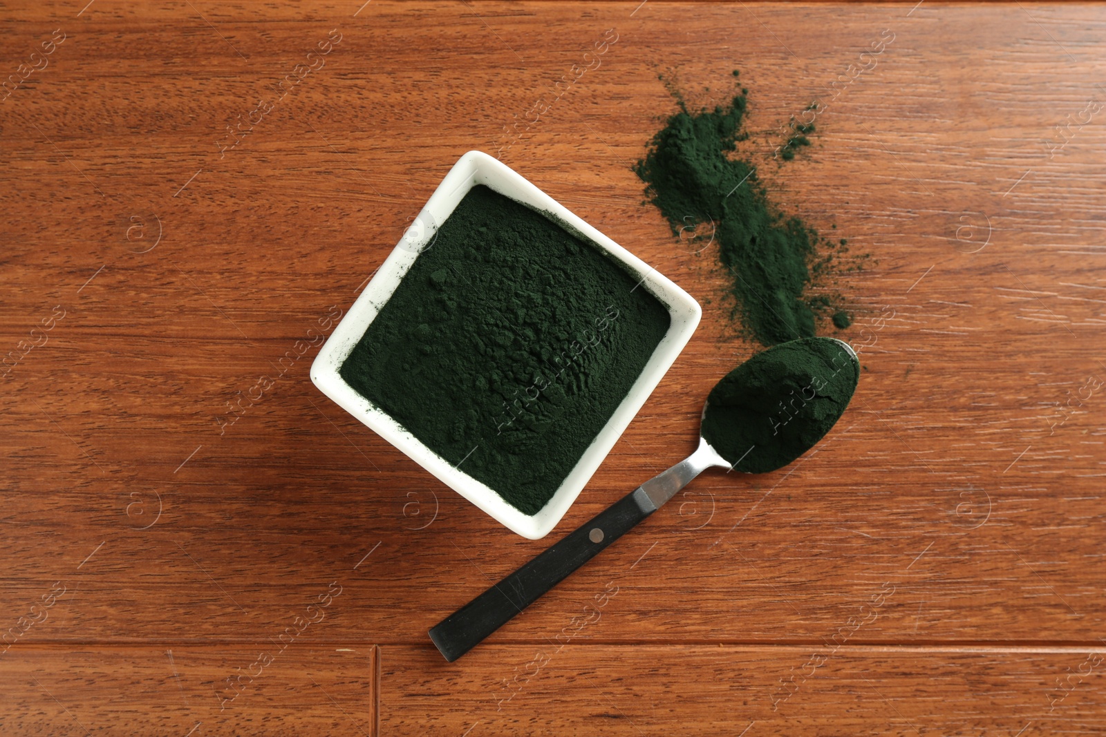 Photo of Superfood powder in bowl and spoon on wooden table, top view