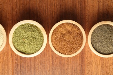 Photo of Different superfood powders in bowls on wooden table, flat lay