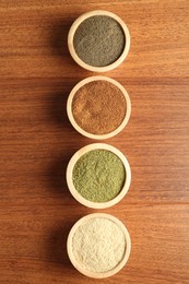 Photo of Different superfood powders in bowls on wooden table, flat lay