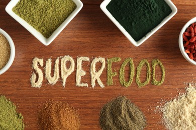 Photo of Word Superfood and different healthy powders on wooden table, flat lay