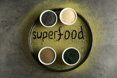 Photo of Word Superfood and different healthy powders on grey table, flat lay