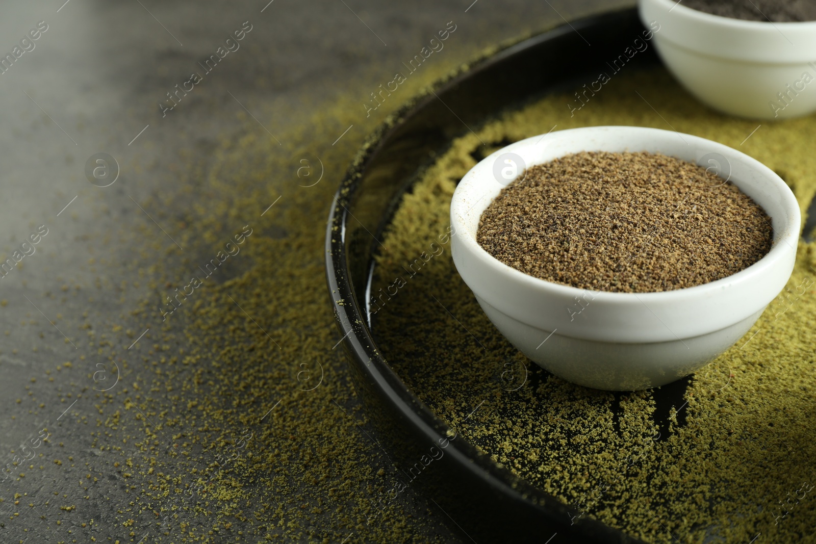 Photo of Superfood powder in bowl on grey table, closeup. Space for text