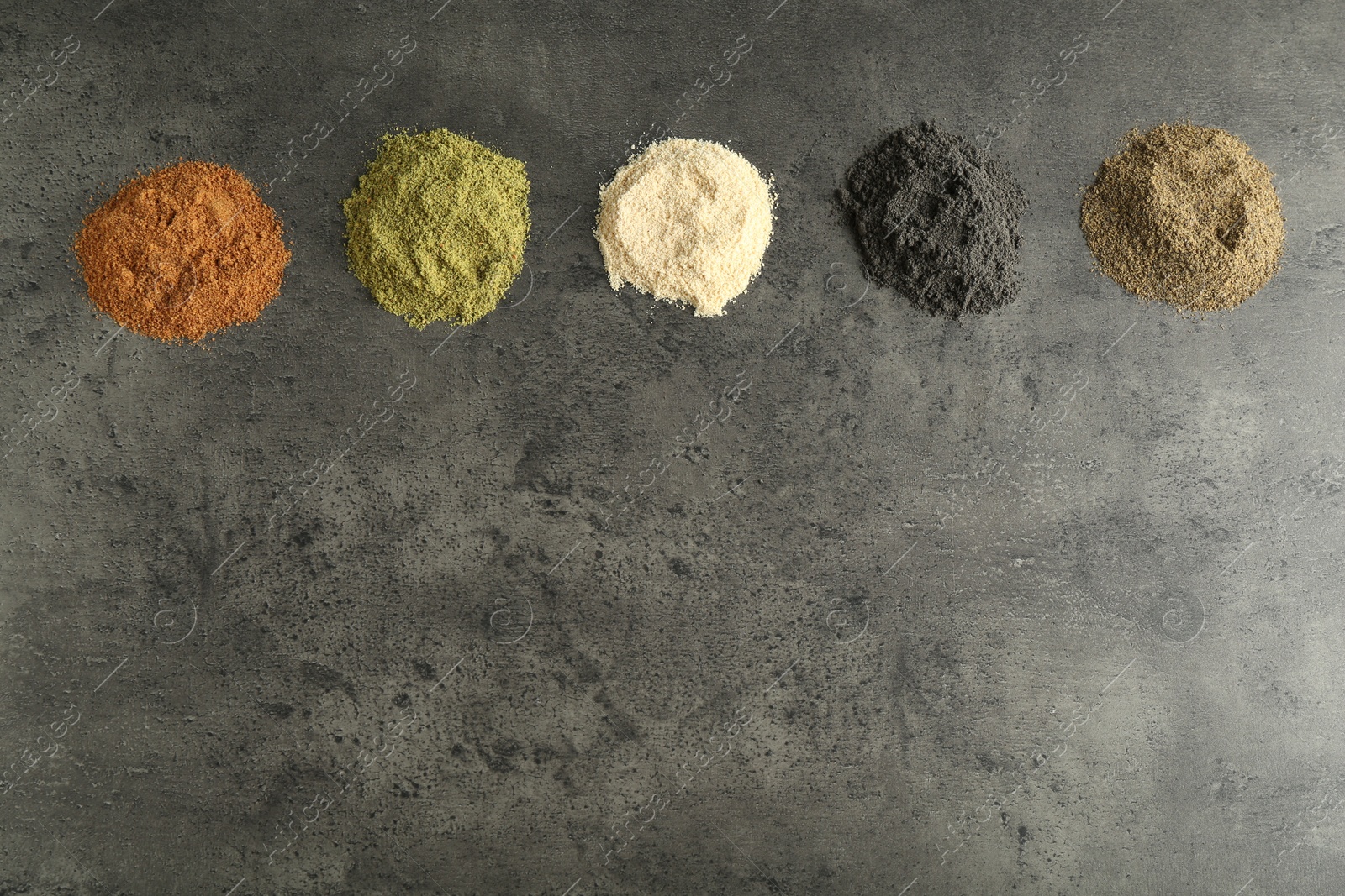 Photo of Different superfood powders on grey table, flat lay. Space for text