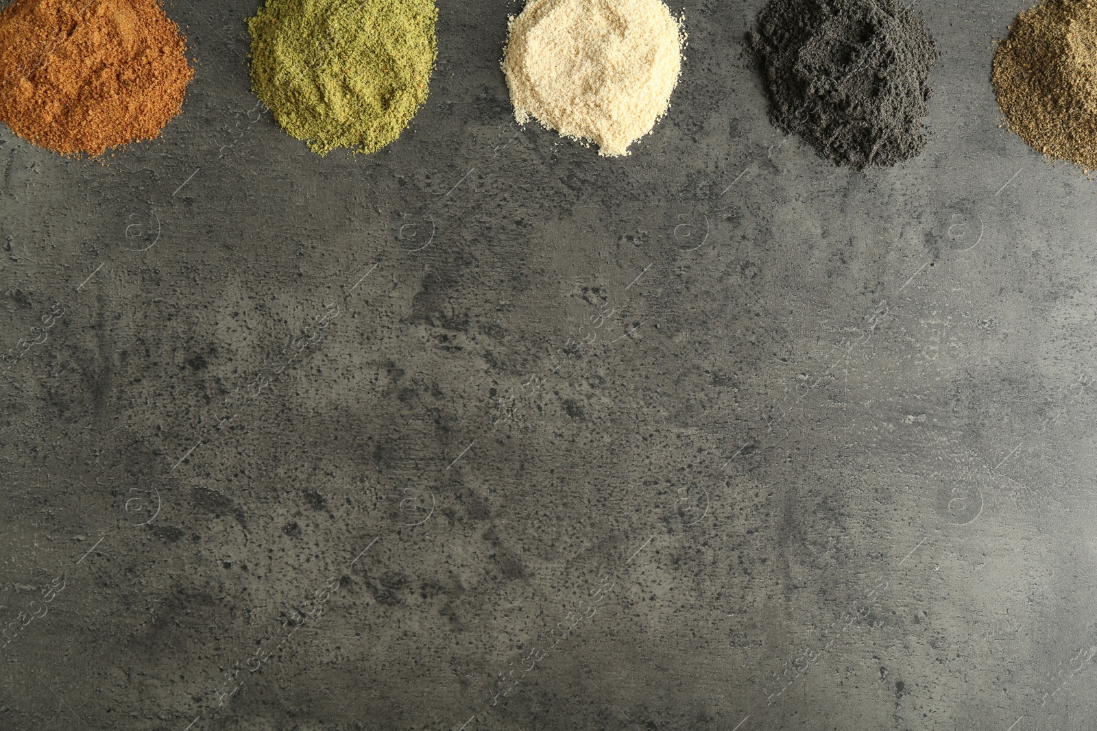 Photo of Different superfood powders on grey table, flat lay. Space for text