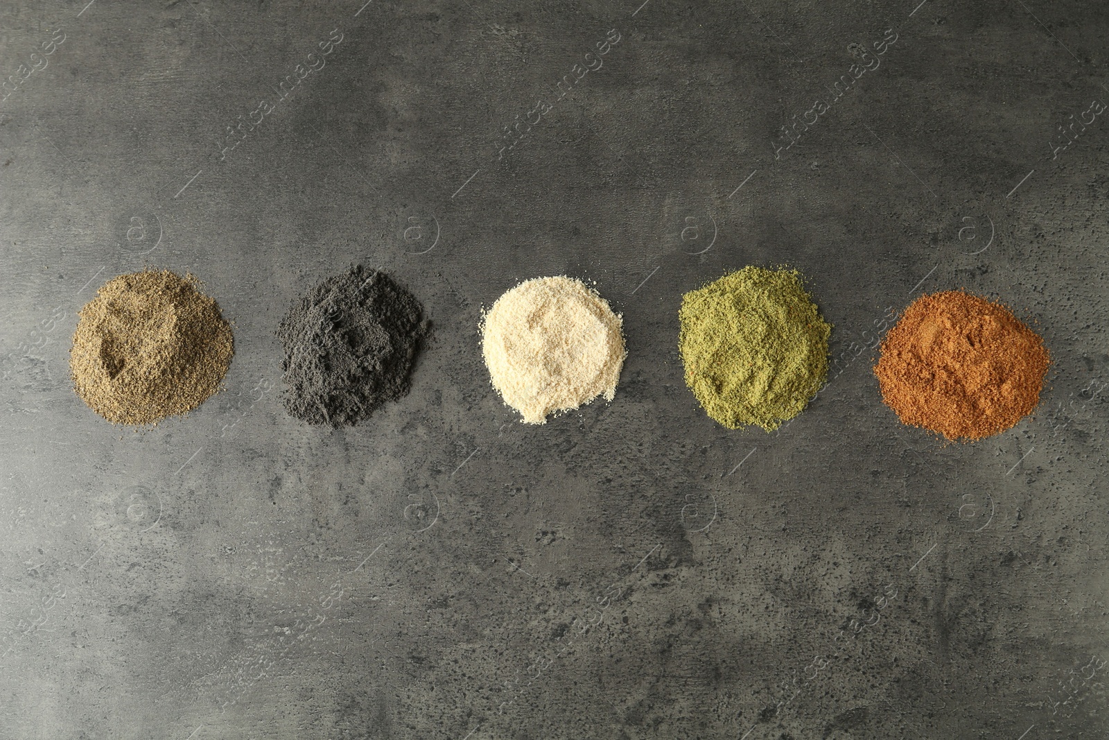 Photo of Different superfood powders on grey table, flat lay