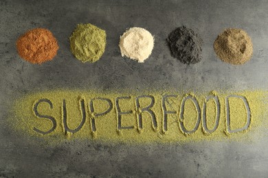 Photo of Word Superfood and different healthy powders on grey table, flat lay