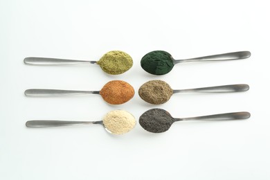 Photo of Different superfood powders in spoons on white background, flat lay