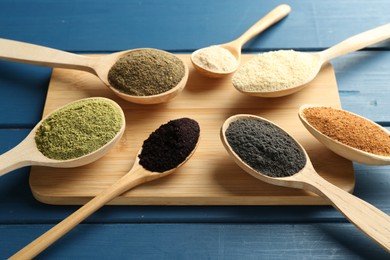 Different superfood powders in spoons on blue wooden table