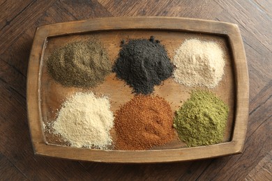 Different superfood powders on wooden table, top view