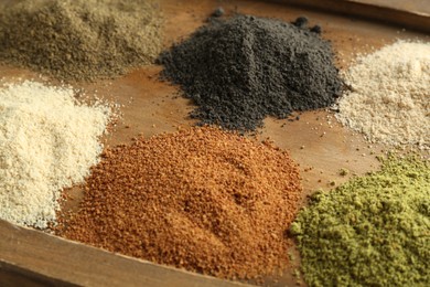 Photo of Different superfood powders on wooden board, closeup