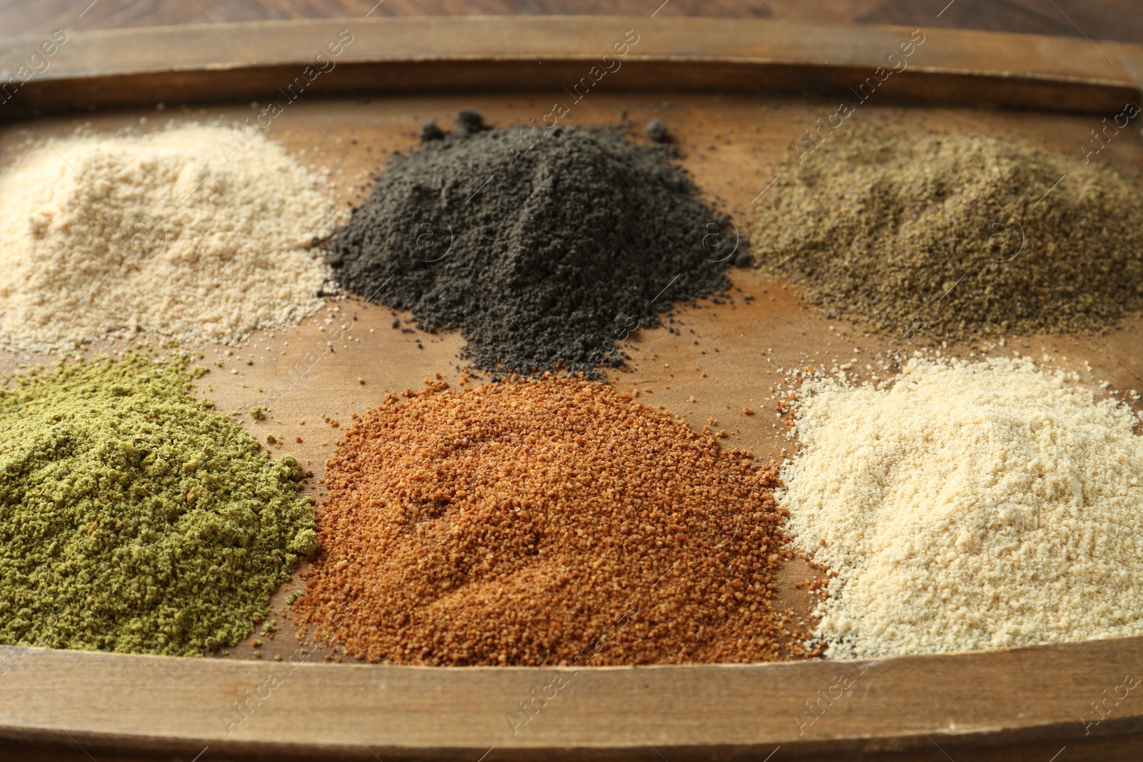 Photo of Different superfood powders on wooden board, closeup