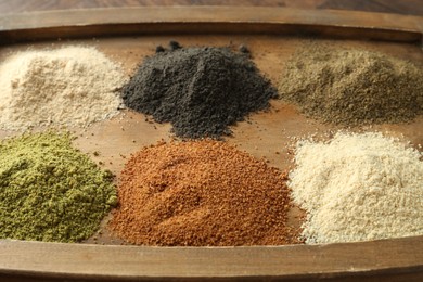 Photo of Different superfood powders on wooden board, closeup