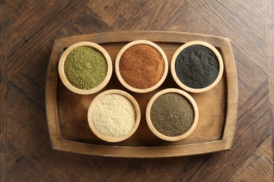 Different superfood powders on wooden table, top view