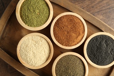 Different superfood powders in bowls on wooden table, top view