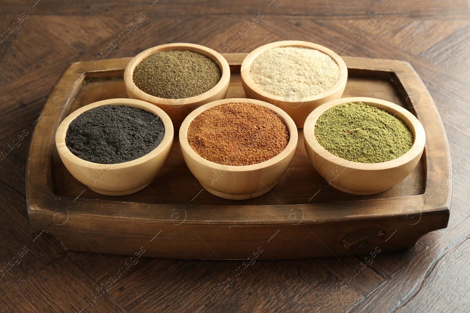 Photo of Different superfood powders in bowls on wooden table