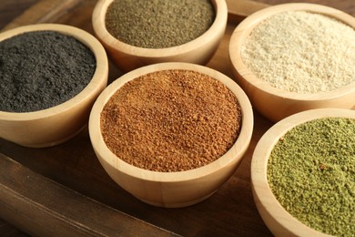 Photo of Different superfood powders in bowls on table, closeup