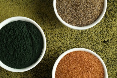 Different superfood powders in bowls on table, flat lay