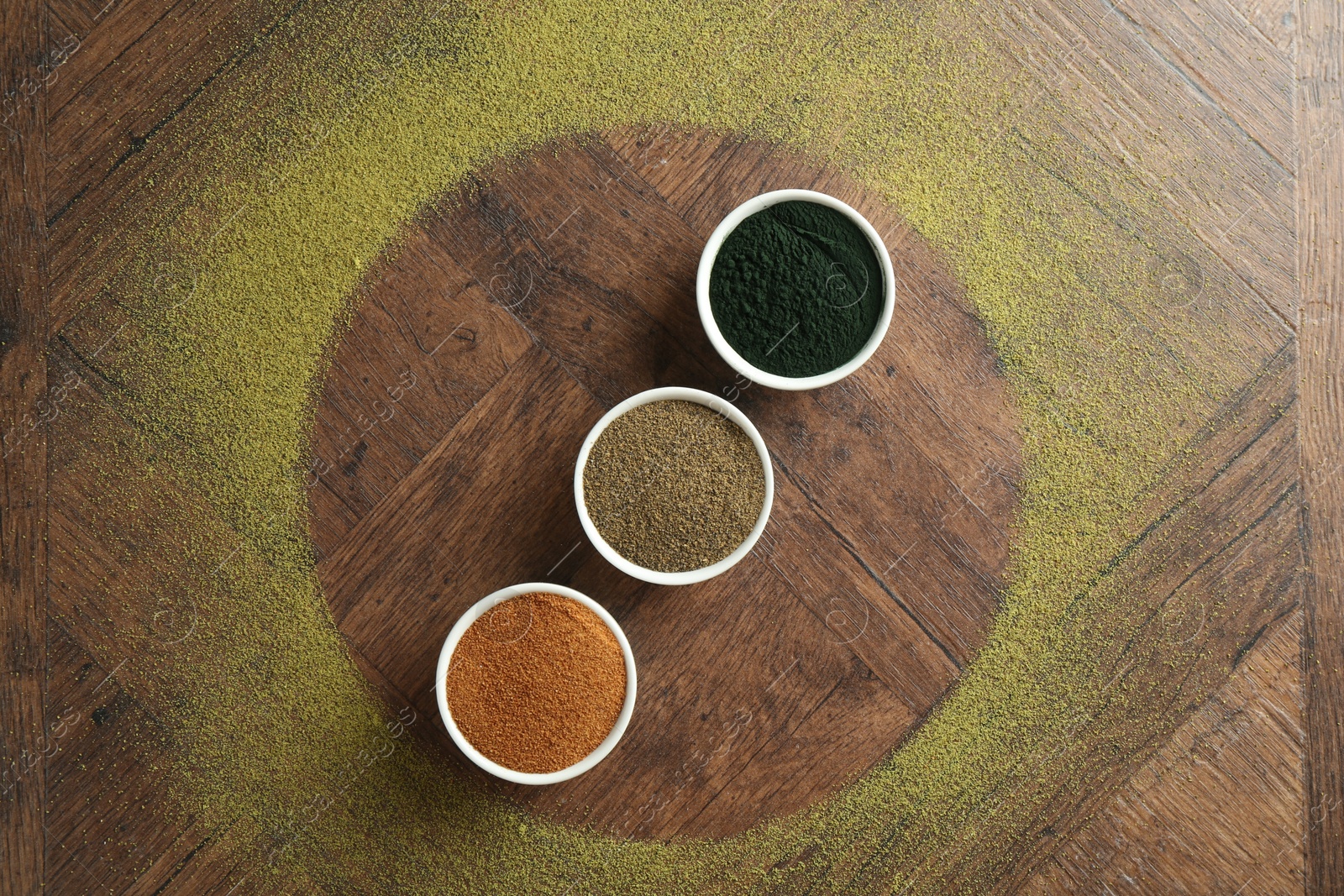 Photo of Different superfood powders in bowls on wooden table, flat lay