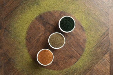 Photo of Different superfood powders in bowls on wooden table, flat lay