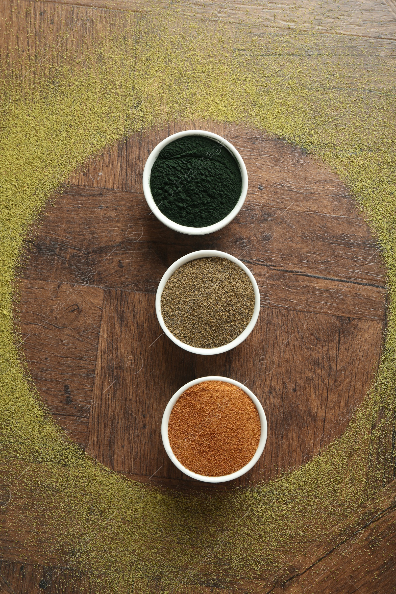 Photo of Different superfood powders in bowls on wooden table, flat lay