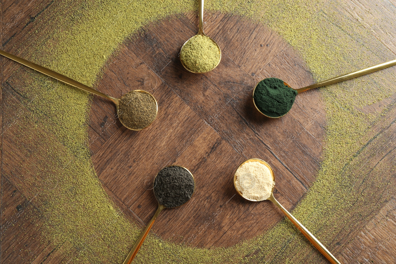 Photo of Different superfood powders in spoons on wooden table, flat lay