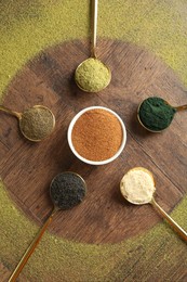 Different superfood powders on wooden table, flat lay