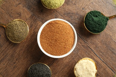 Photo of Different superfood powders on wooden table, flat lay