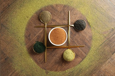 Photo of Different superfood powders on wooden table, flat lay