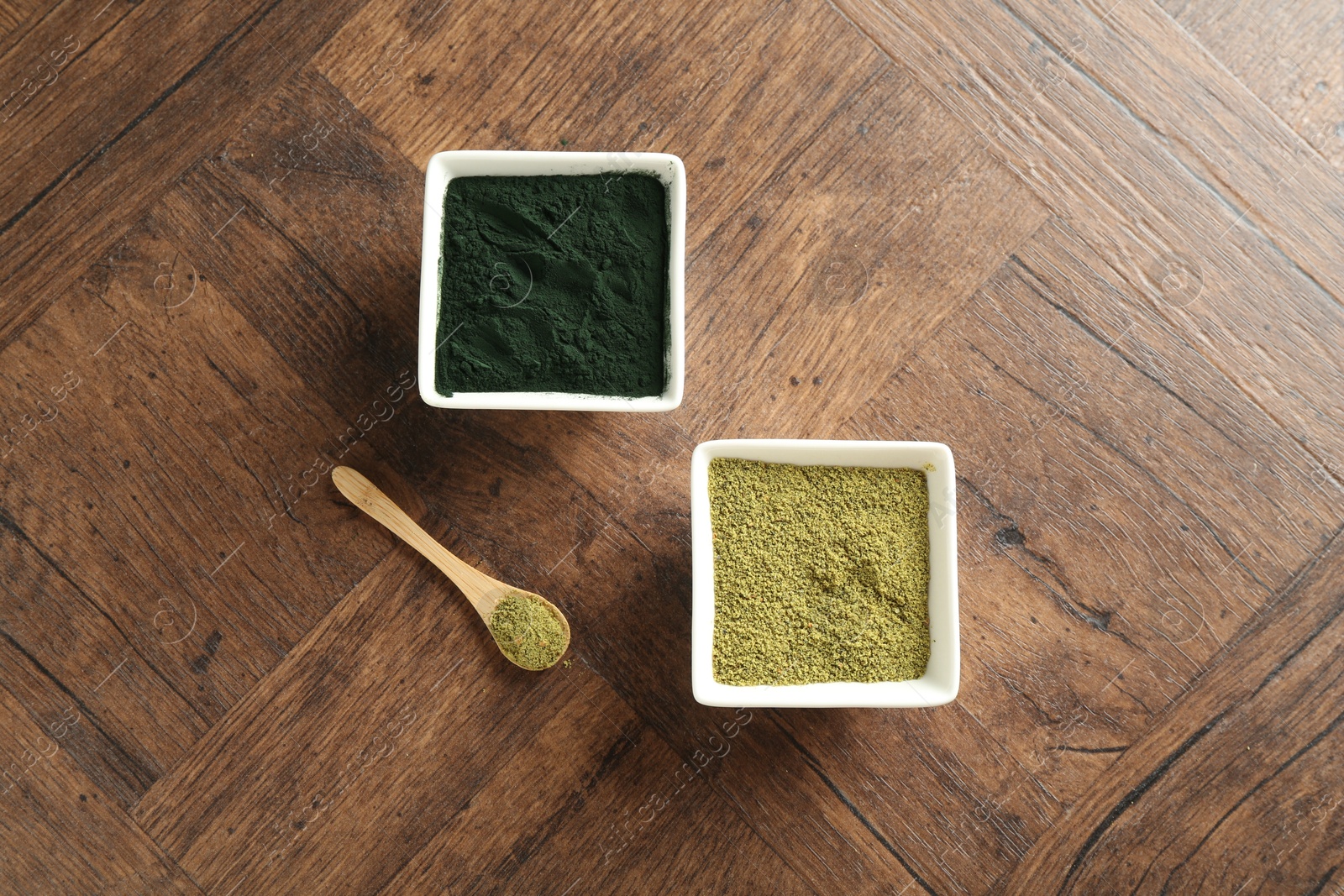 Photo of Different superfood powders in bowls and spoon on wooden table, top view