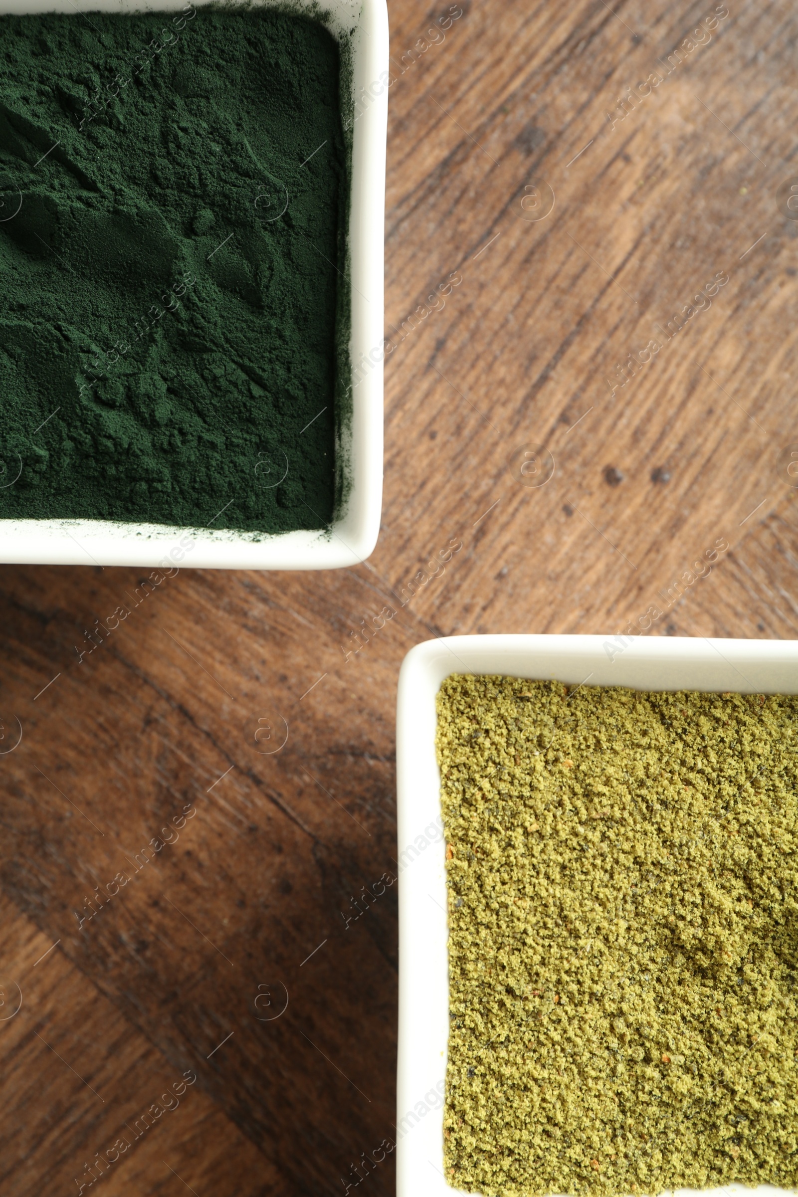 Photo of Different superfood powders in bowls on wooden table, top view