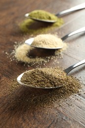 Different superfood powders in spoons on wooden table, closeup