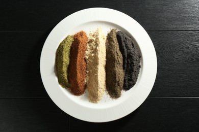 Different superfood powders on black wooden table, top view