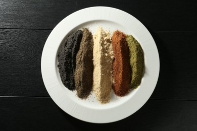 Photo of Different superfood powders on black wooden table, top view