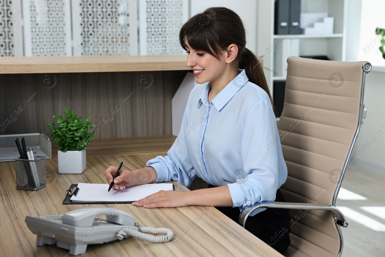 Photo of Professional receptionist working at wooden desk in office