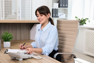 Professional receptionist working at wooden desk in office