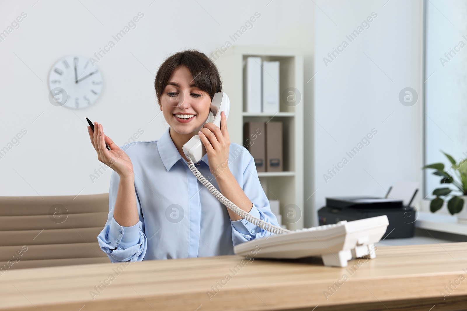 Photo of Professional receptionist talking on phone in office