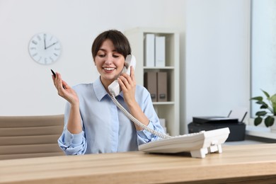 Professional receptionist talking on phone in office