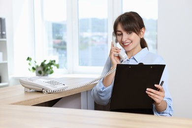 Professional receptionist talking on phone in office