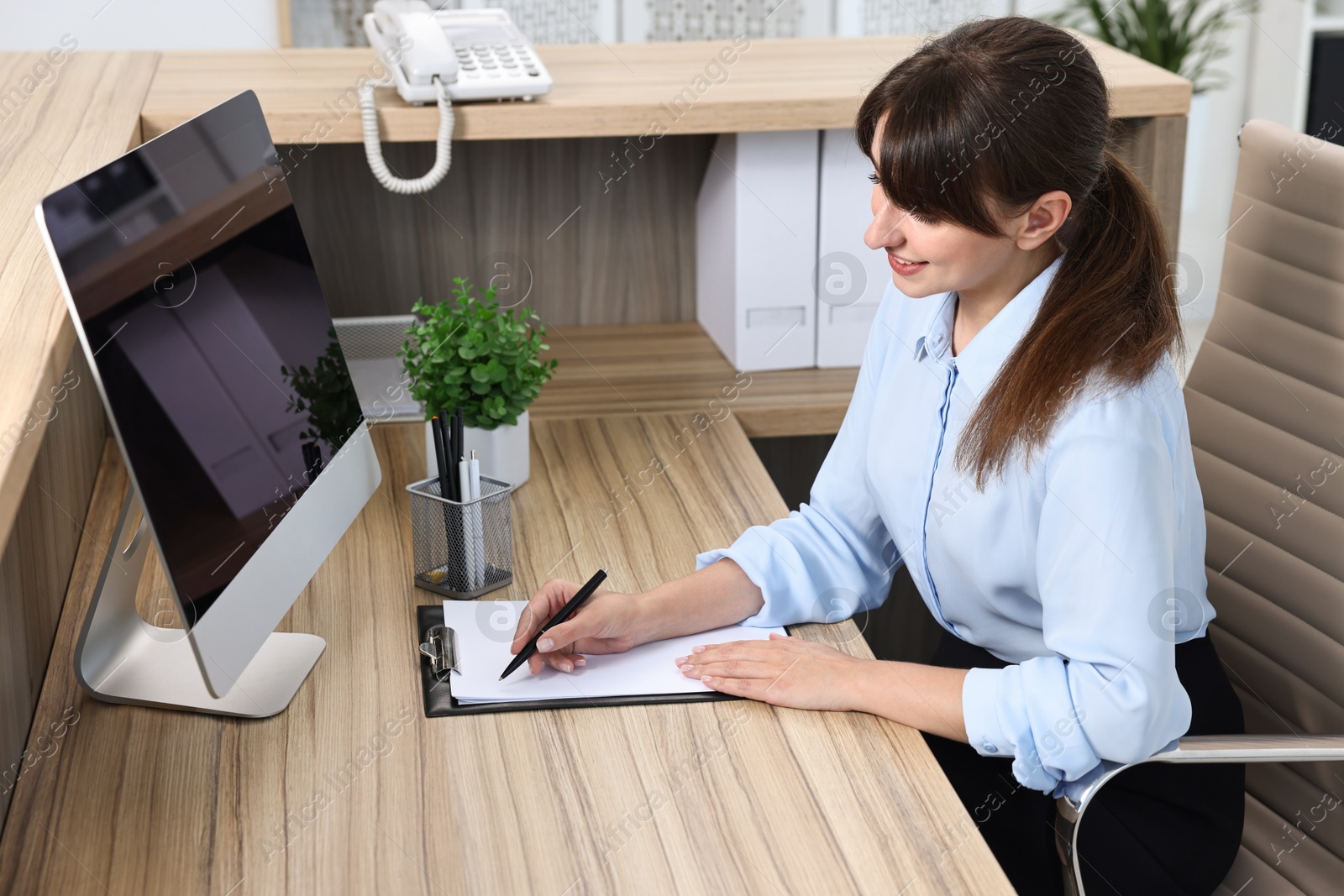 Photo of Professional receptionist working at wooden desk in office