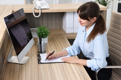 Professional receptionist working at wooden desk in office