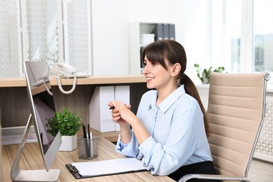 Professional receptionist working at wooden desk in office