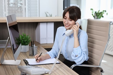 Professional receptionist talking on phone in office