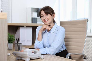 Photo of Portrait of receptionist at wooden desk in office